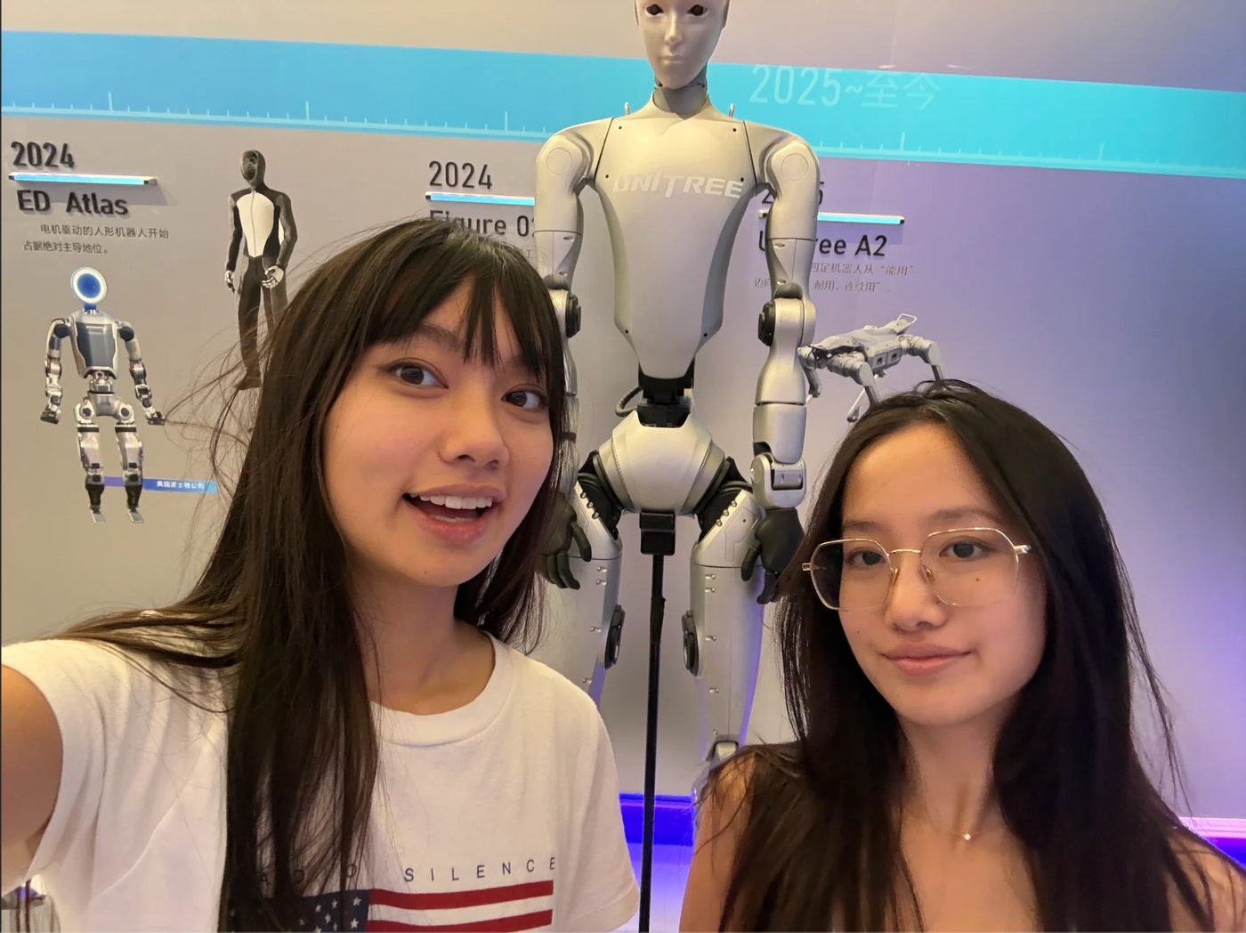 Michelle and her sister taking a selfie in front of a humanoid robot exhibit